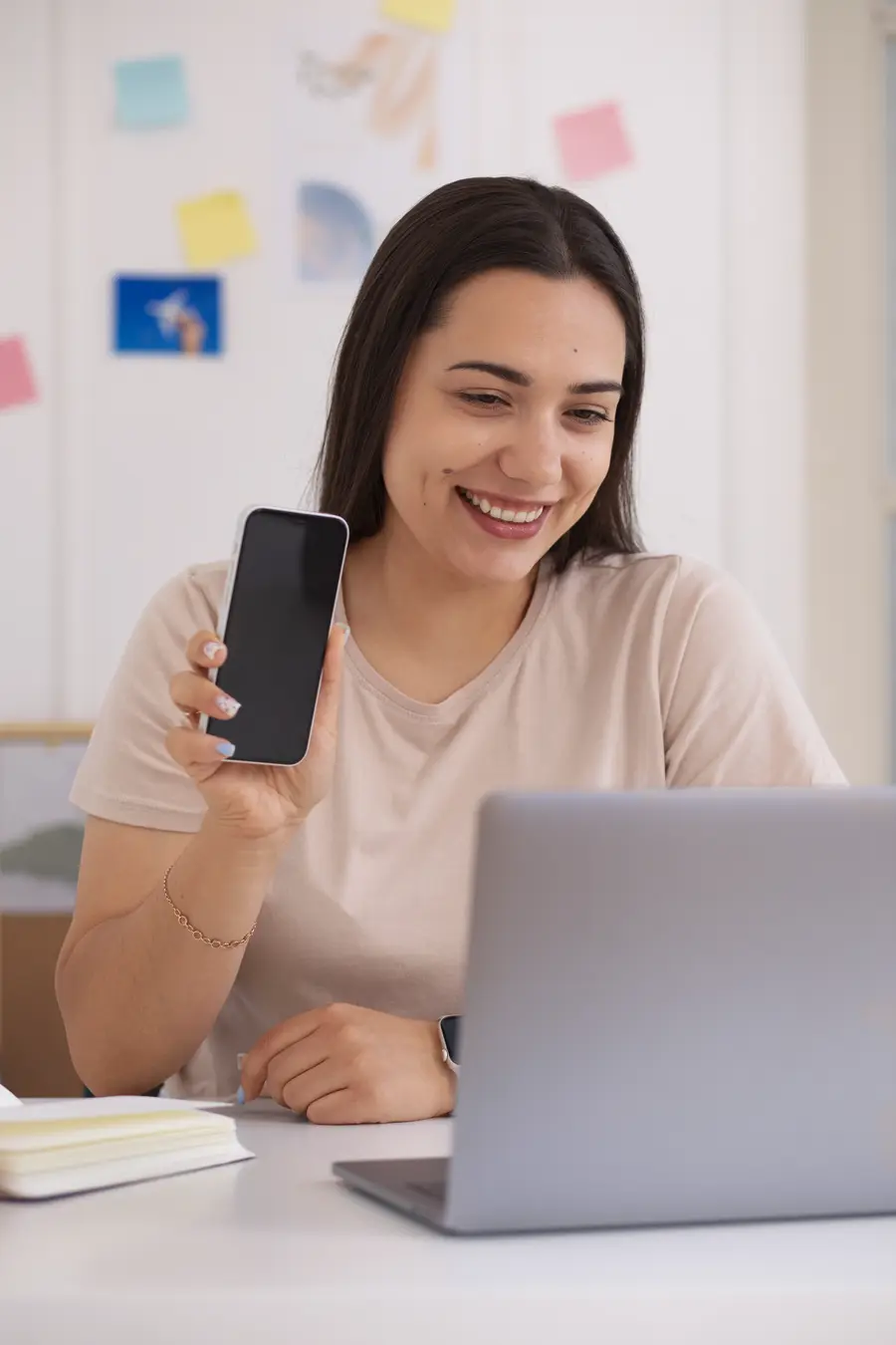 Asesora mostrando su celular frente a su laptop
